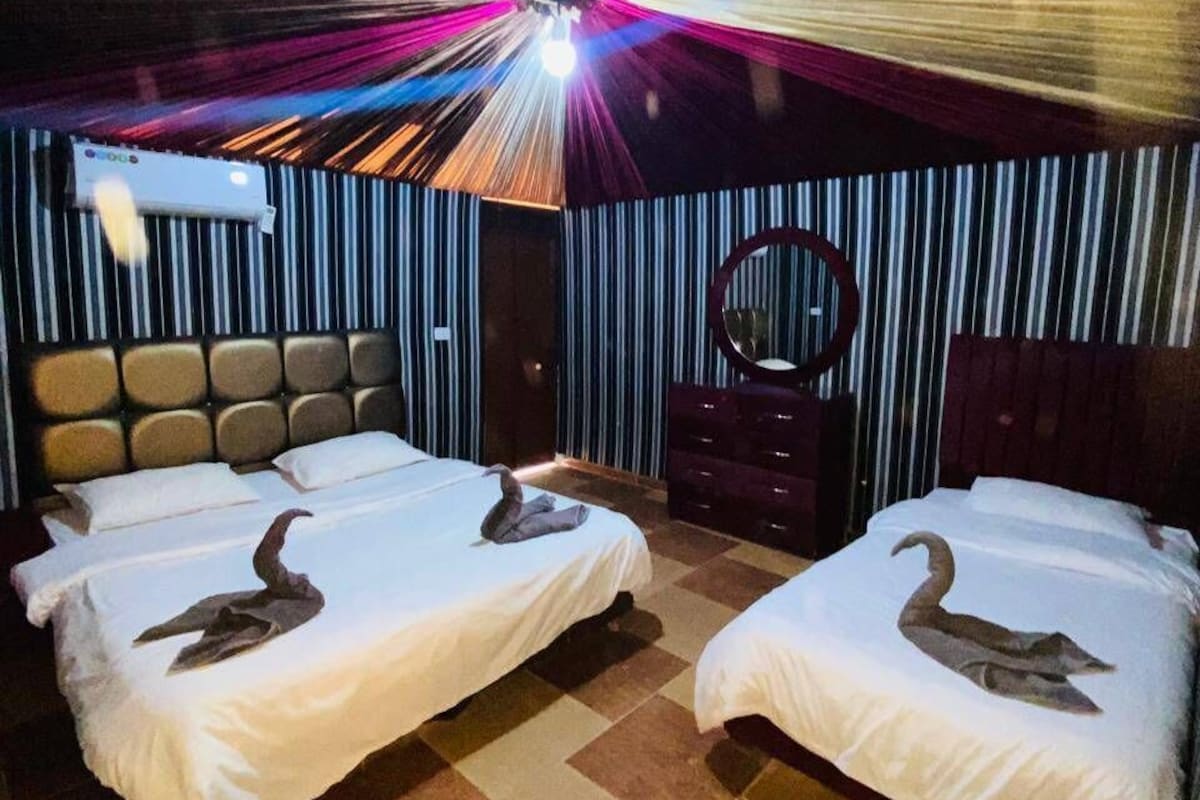 A hotel room with two beds, a mirror, and a ceiling light fixture.