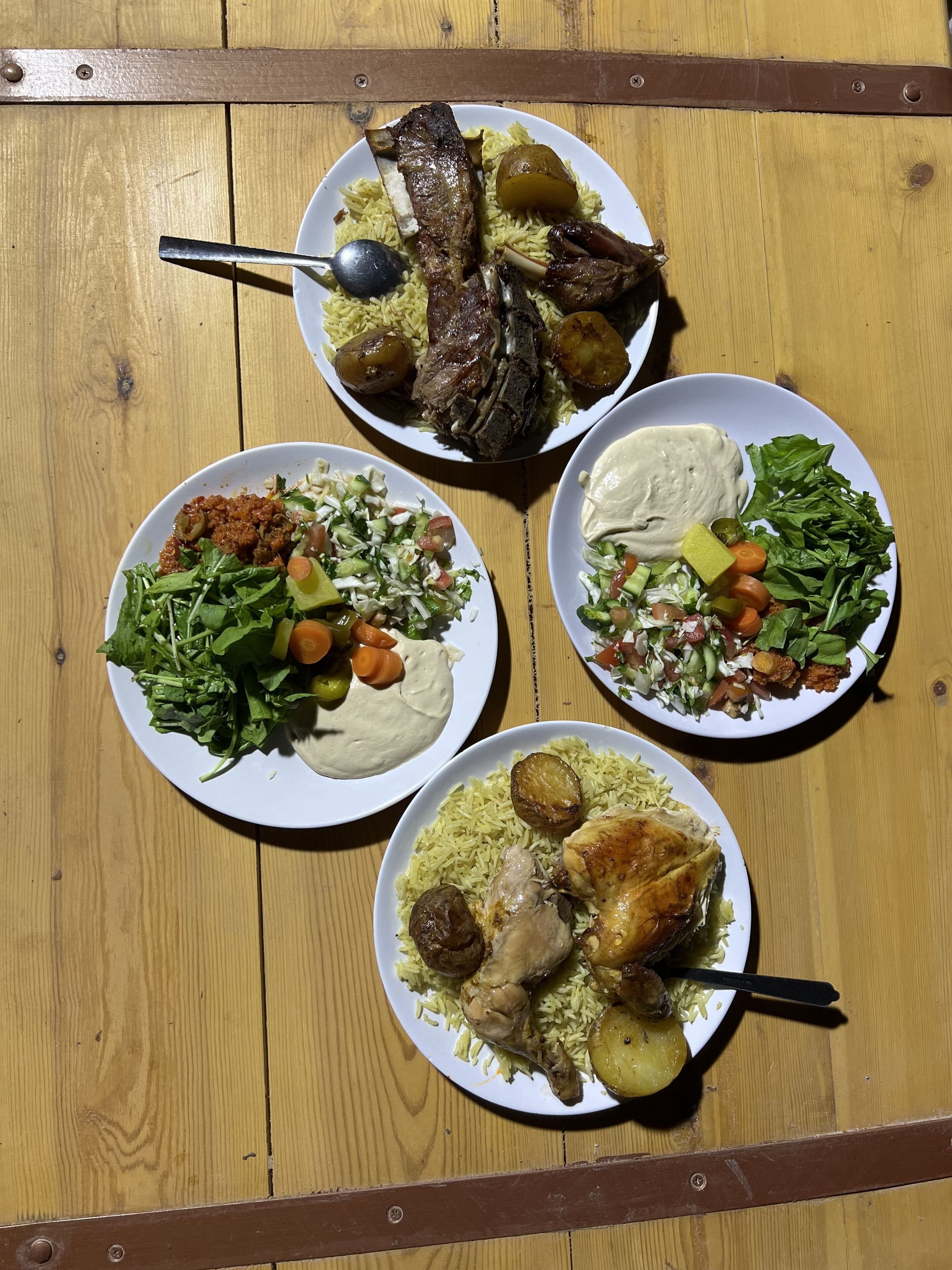 A wooden table with four plates of food.