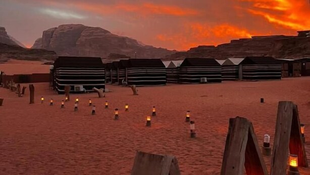 A desert landscape with wooden structures and lanterns. - Sand Rose Camp - Hillawi Camp (Wadi Rum)