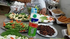 A buffet setup with various food items including salads, fruits, and a carton of milk. - Sand Rose Camp - Hillawi Camp (Wadi Rum)