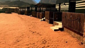 A desert landscape with a row of yurts and a sandy path. - Sand Rose Camp - Hillawi Camp (Wadi Rum)