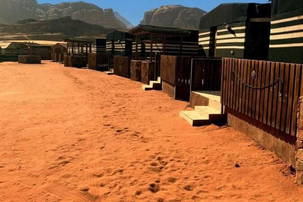 A desert landscape with a row of yurts and a sandy path.