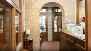 A hallway with brick walls, wooden doors, and a desk with papers. - Hotel San Miguel (Segovia)