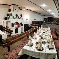 Un restaurante con mesas largas compartidas dispuestas para comer, bancos y una chimenea.