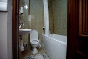 Une salle de bain avec des toilettes, un lavabo et une baignoire.