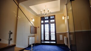 A hotel lobby with a blue carpet, a chandelier, and a large window with a view. - Astoria (Chisinau)