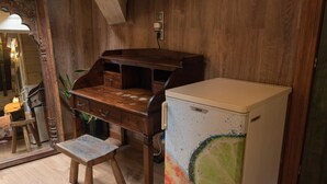 Ein Holztisch mit Schubladen, ein kleiner Hocker und ein Kühlschrank mit farbigem Muster.