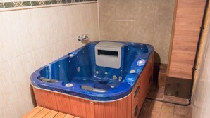 Eine Holzafütte Holzwanne mit blauem Innenraum, einer Steuerung und einer Sitzbank in einem gefliesten Raum.