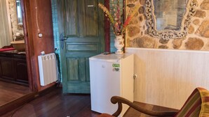 Eine kleine Küche mit Kühlschrank, Holztür, Steinwand und Spiegel.
