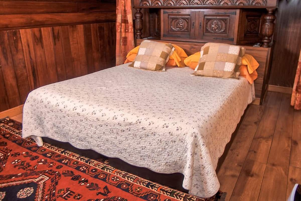 Ein Bett mit einem gemusterten Bettbezug, zwei Kissen und einem hölzernen Kopfteil.