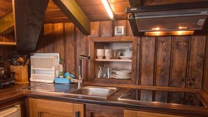 Una cucina in legno con lavello incassato, scolapiatti e un piccolo ripiano con stoviglie.