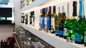 A bar with shelves of various liquor bottles and glasses. - CE Napfény Hotel (Siófok)
