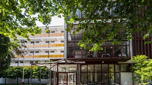 A building with a covered entrance, outdoor seating area, and a multi-story structure with balconies. - CE Napfény Hotel (Siófok)