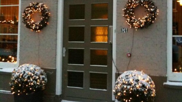 A building with a sign reading "DE PASSANT" and two wreaths on the door. - B&B de Passant (Breskens)