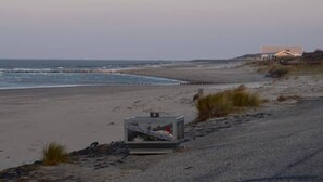 A beach with a building in the background, a road, and a cage-like structure on the sand. - B&B de Passant (Breskens)
