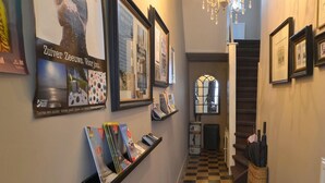 A hallway with framed pictures on the walls, a staircase, and a checkered floor. - B&B de Passant (Breskens)