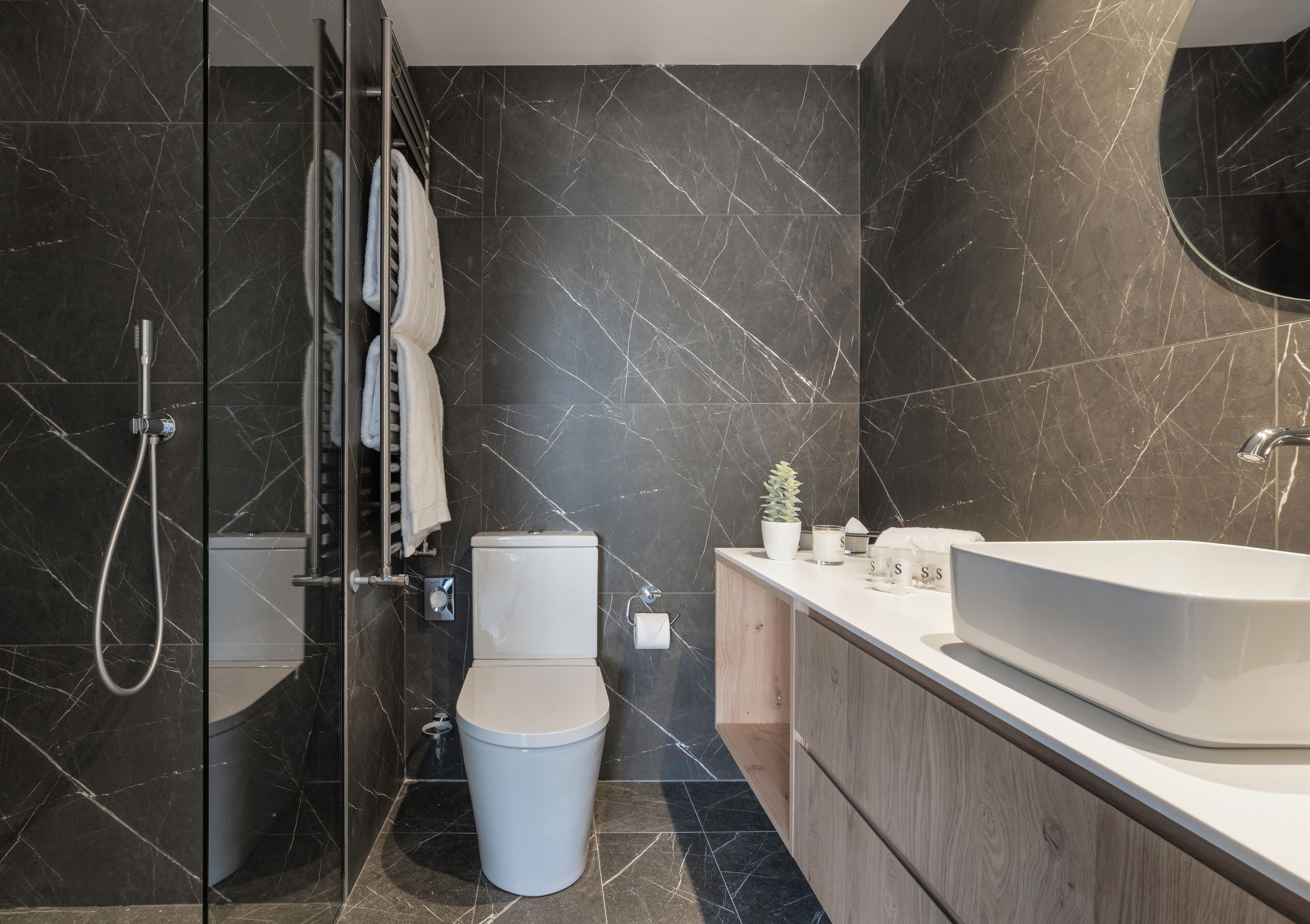 A modern bathroom with a glass shower enclosure, a toilet, a sink, and a vanity.