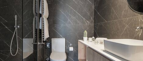A modern bathroom with a glass shower enclosure, a toilet, a sink, and a vanity.