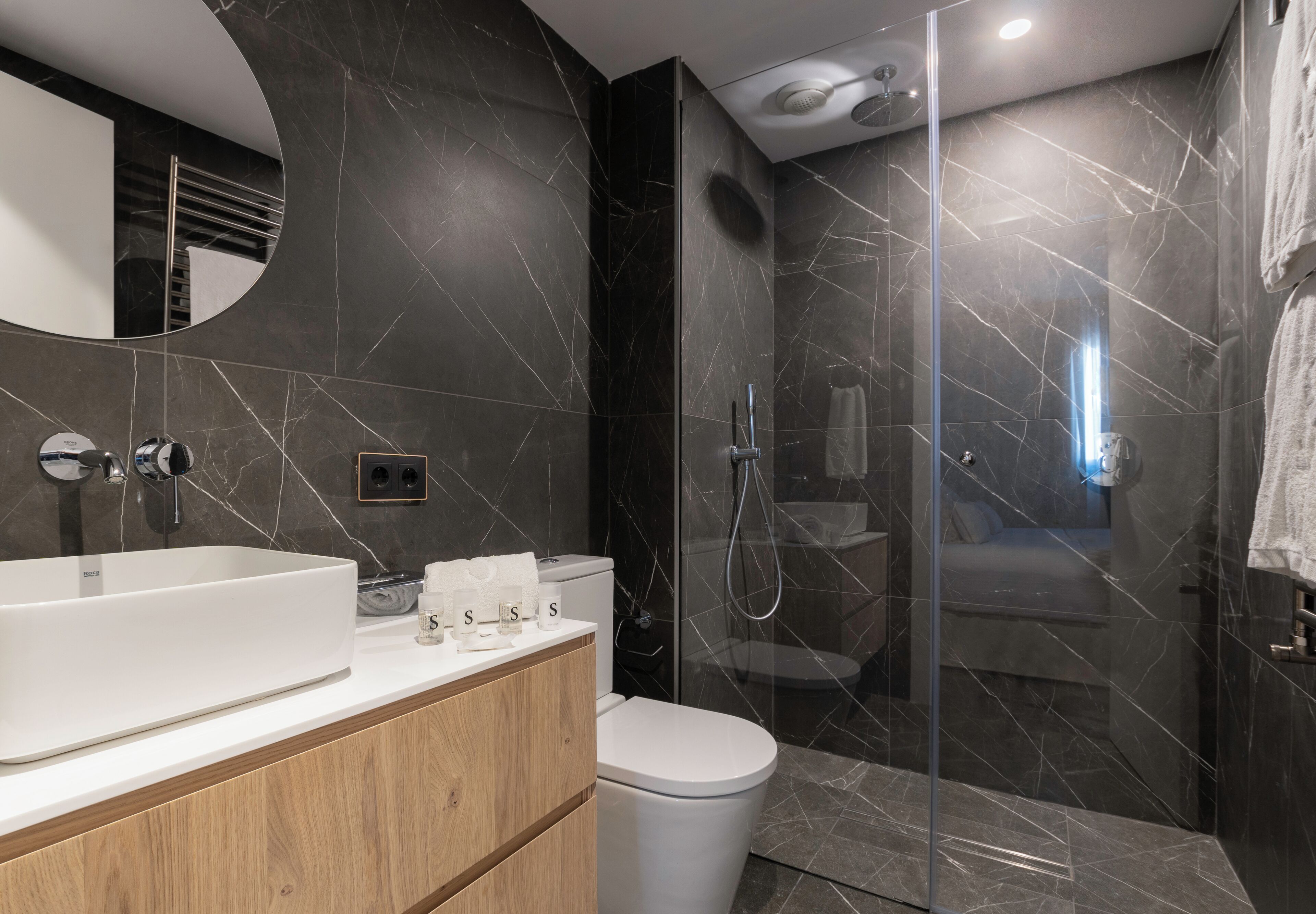 A modern bathroom with a large white sink, a toilet, and a glass-enclosed shower area.