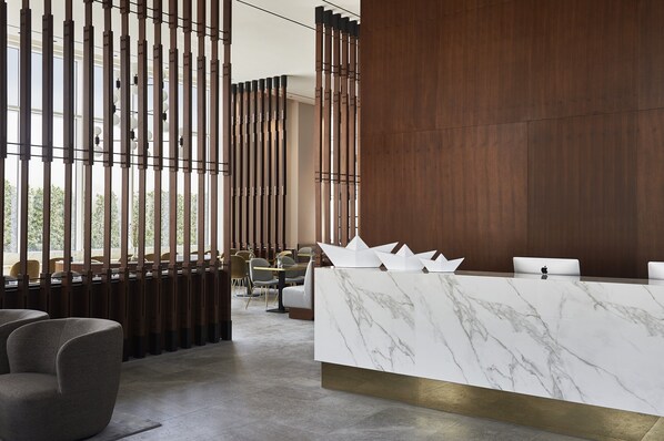 A modern reception area with a marble counter, wooden paneling, and seating arrangements.