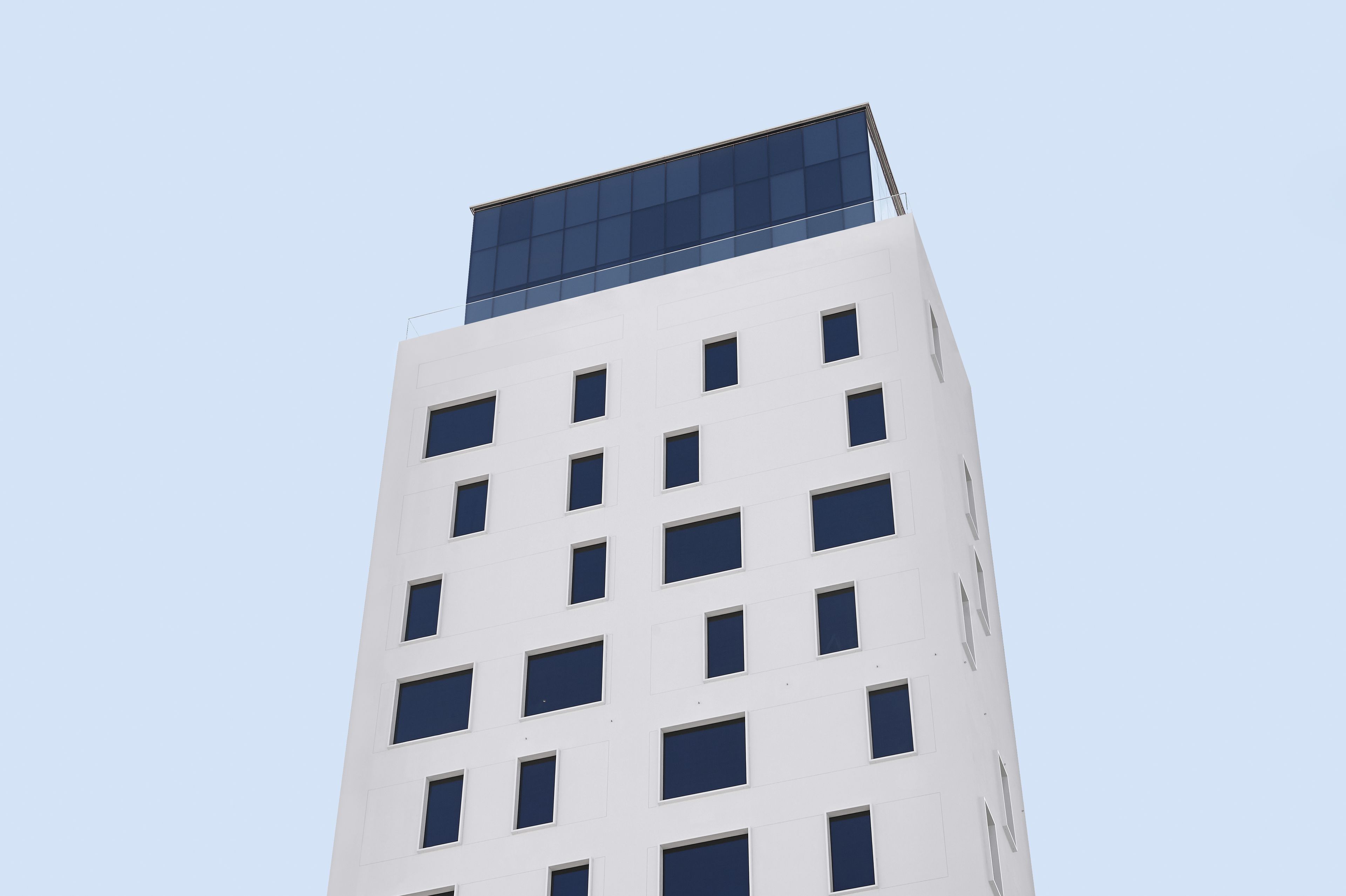 A tall, modern building with a flat roof and numerous windows.