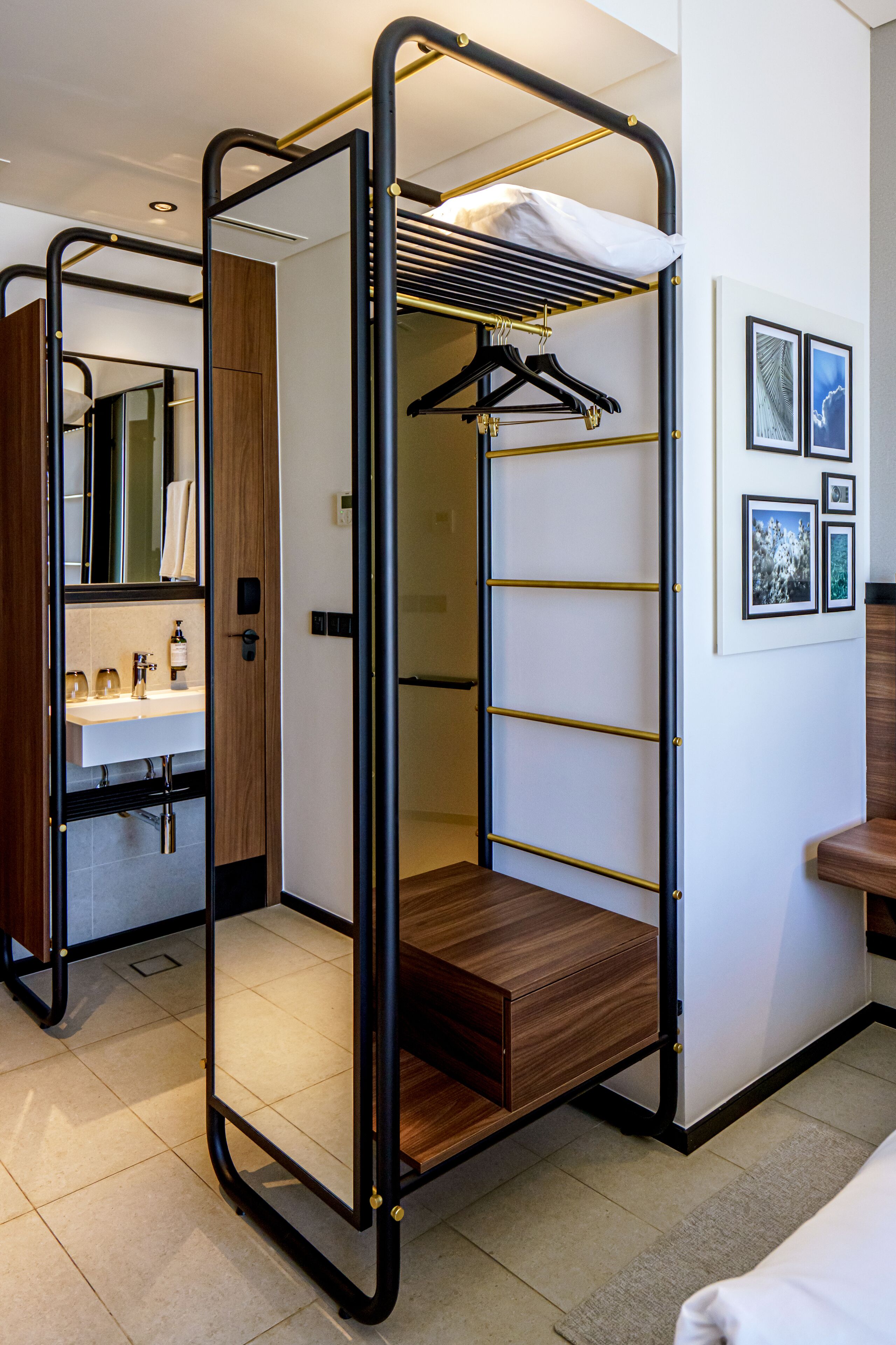 Habitación compacta y moderna con literas, un armario de madera, un lavamanos y cuadros enmarcados en la pared.
