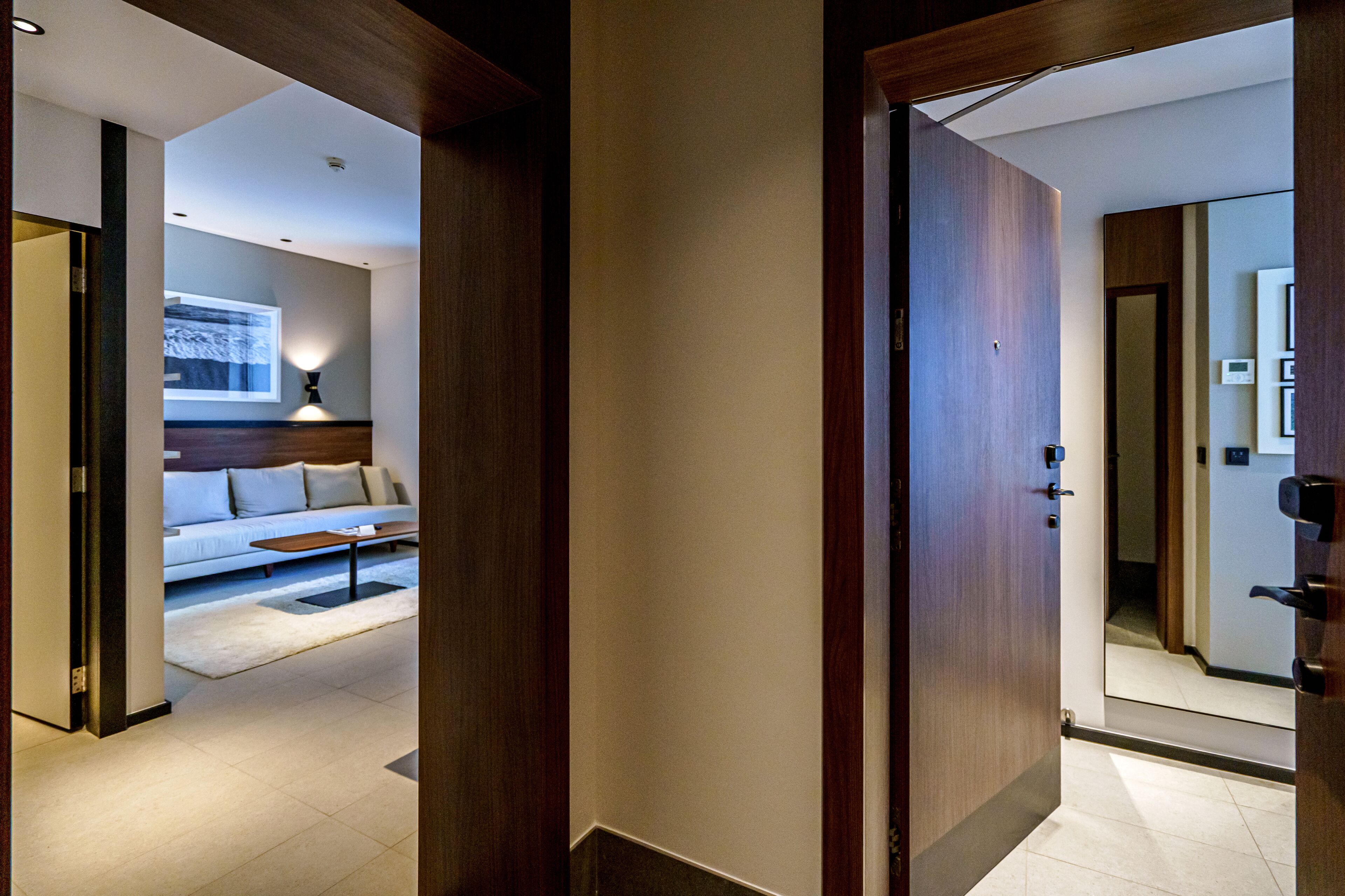 Una camera d'albergo moderna con una porta in legno, un divano bianco e un tavolino da caffè.