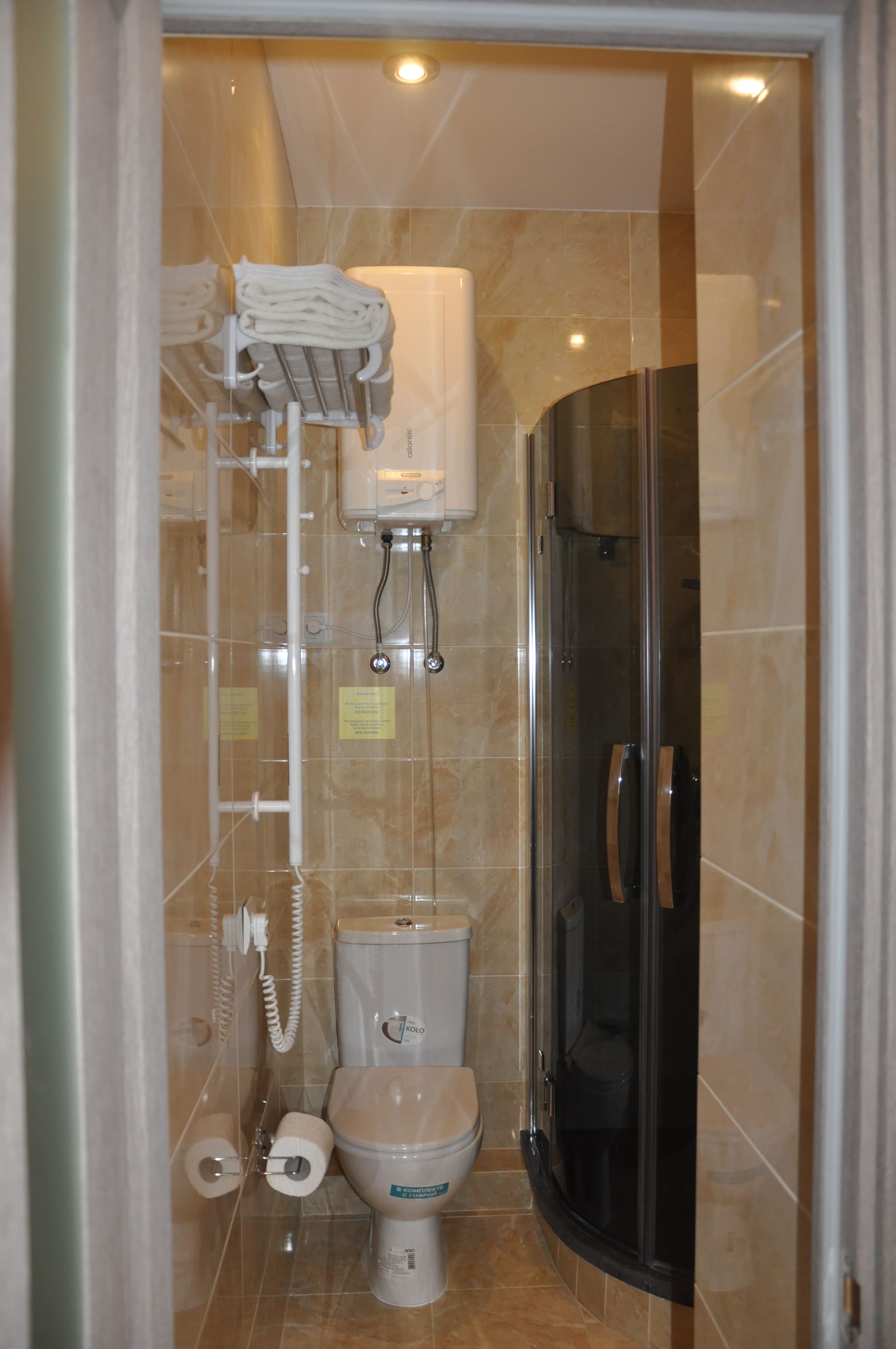 Un baño con inodoro, ducha envuelta en vidrio y un perchero con toallas.