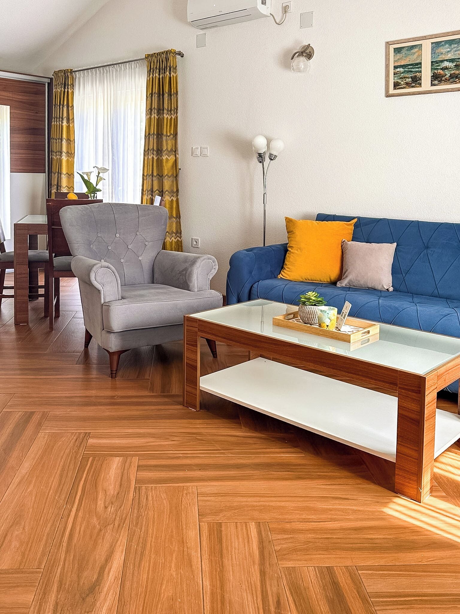 Una sala de estar con sofá, sillón, mesa de centro de madera y un comedor con mesa y sillas.