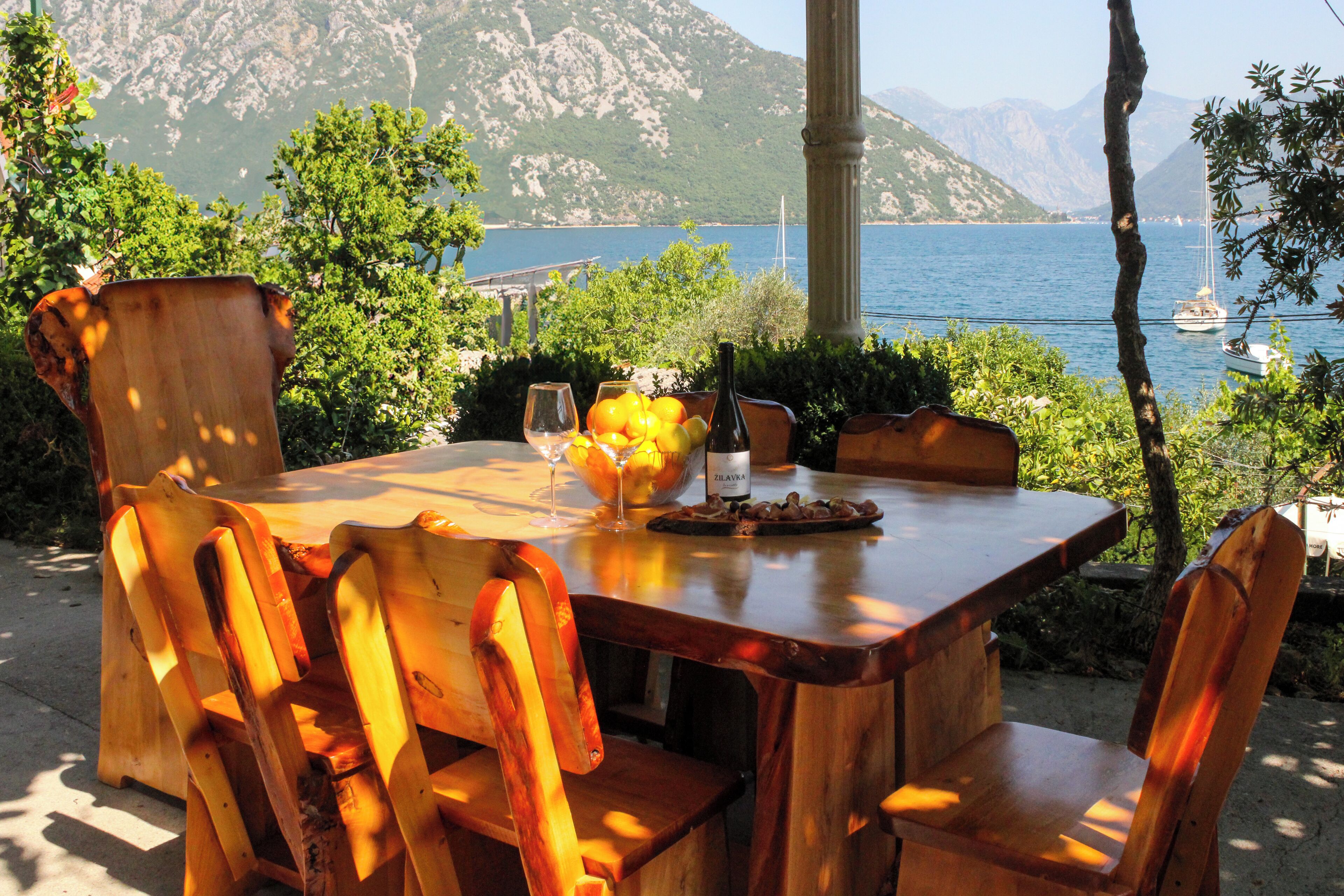 A wooden table with chairs, a bottle, and a bowl of fruit.