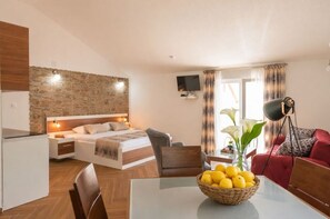 A modern hotel room with a bed, a desk, a dining table, and a TV. - Apartments Stella del Mare (Risan)