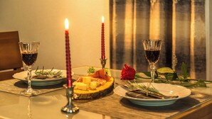 A dining table set with plates, glasses, a candle, a rose, and a wooden board with food. - Apartments Stella del Mare (Risan)