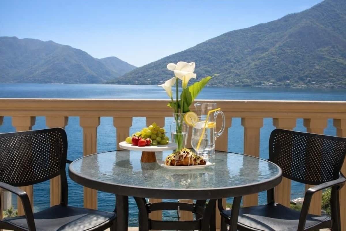 Une table avec une carafe, une assiette de raisins et un arrangement floral composé de fleurs blanches.