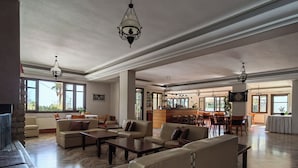 A spacious living area with leather sofas, a coffee table, and a dining area with bar stools. - Corali Hotel (Kymi-Aliveri)