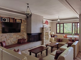 Una sala de estar con chimenea de piedra, sofás de cuero, un televisor de pantalla plana y un comedor con mesa y sillas.
