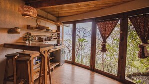 A kitchen with wooden countertops, stools, and a large window with curtains. - Baraka Atitlan - Lake & Beach (San Marcos La Laguna)