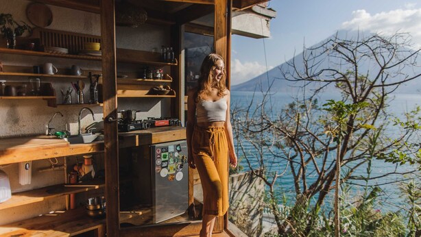 A rustic kitchen with wooden shelves and a refrigerator, overlooking a scenic mountain view. - Baraka Atitlan - Lake & Beach (San Marcos La Laguna)