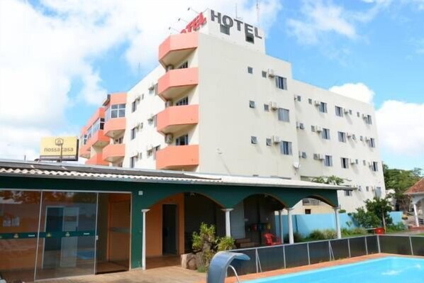 Un hotel con piscina, varios balcones y un letrero que indica un restaurante.