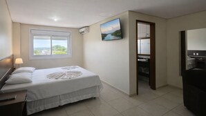 Une chambre à coucher avec un lit, une télévision, une fenêtre donnant sur un beau paysage et une salle de bain visible à travers une porte ouverte.