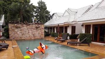 Relax by the rectangular pool surrounded by lounge chairs and a small table.