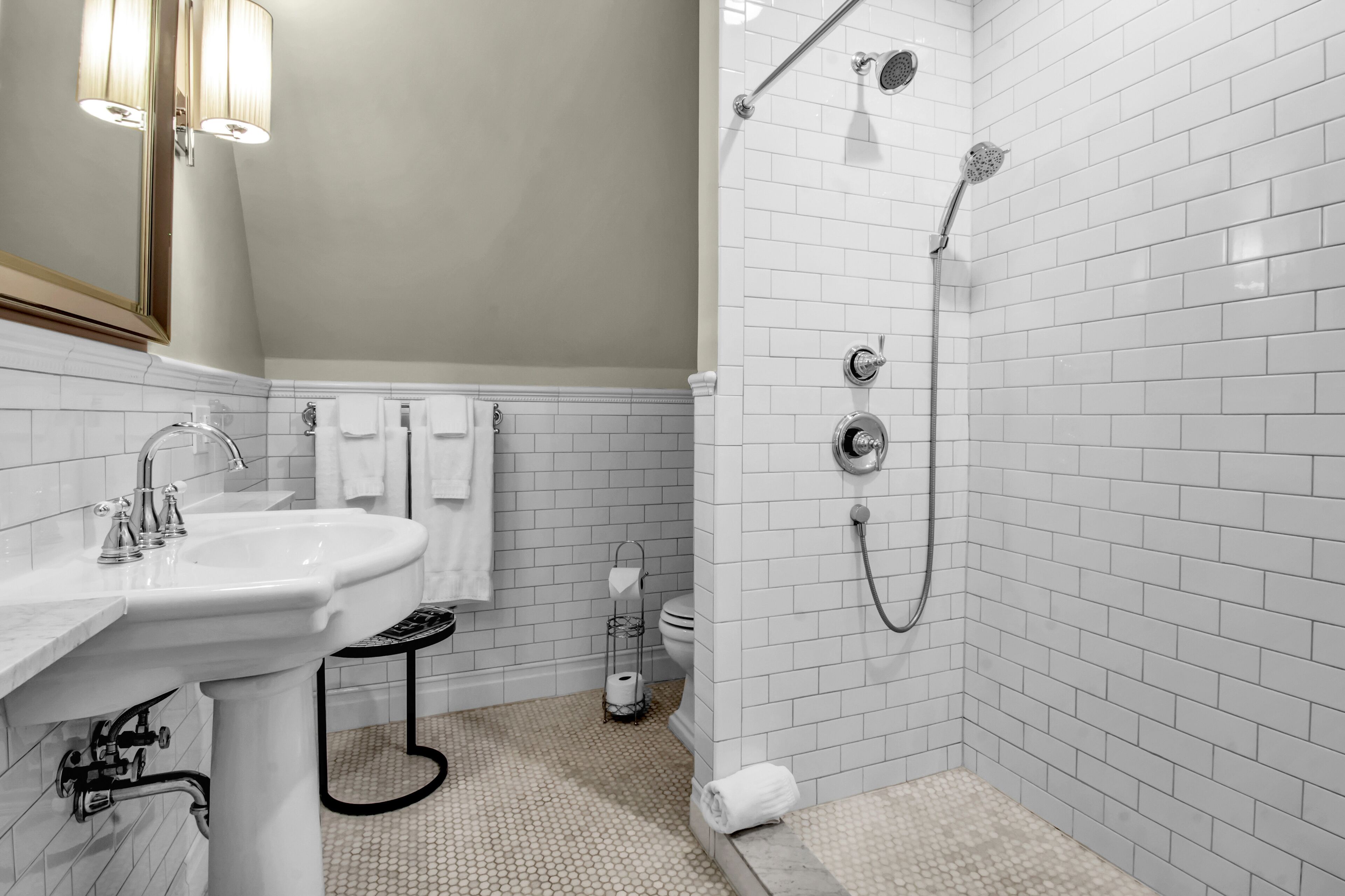 Un baño moderno con un lavamanos blanco, ducha con cabezal de ducha manual y un inodoro.