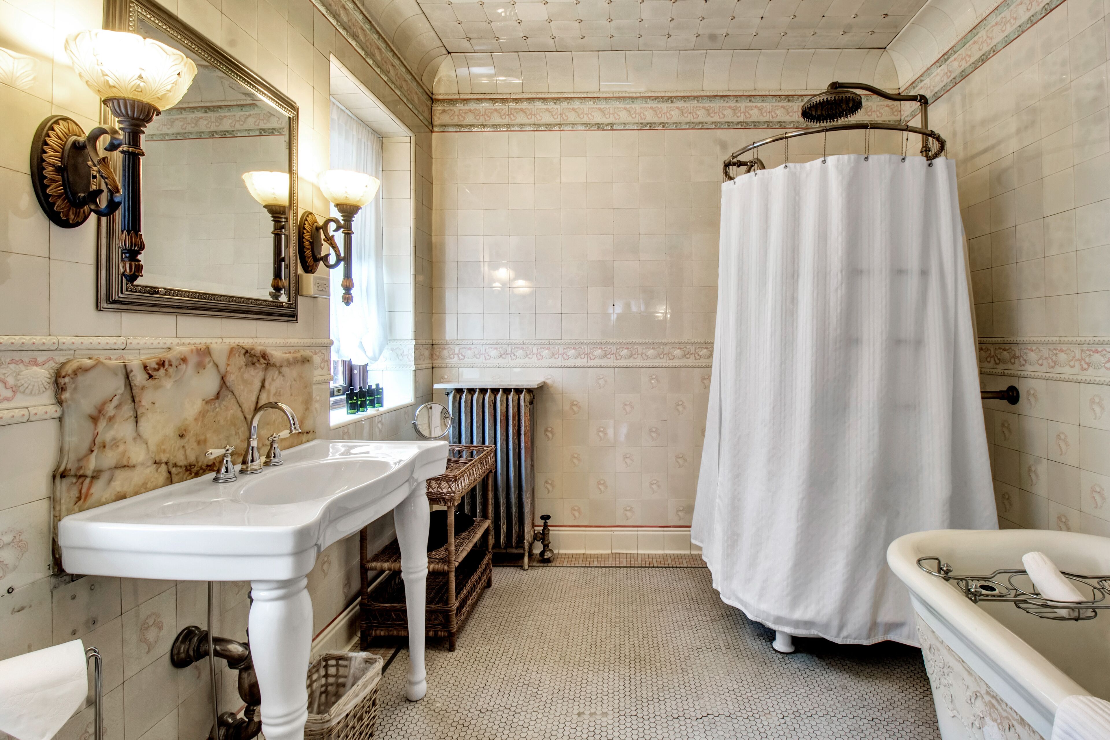 A bathroom with a white sink, a mirror, a shower curtain, and a bathtub.