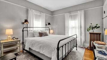 A bedroom with a bed, bedside tables, a desk, and a chair.