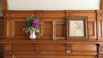 A wooden mantelpiece with a vase of flowers and a framed picture.