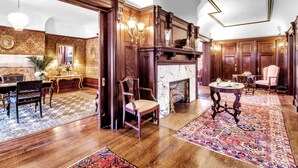 A spacious room with a wooden floor, a fireplace, a dining area with a table and chairs, and a large rug. - InnBuffalo off Elmwood (Buffalo)