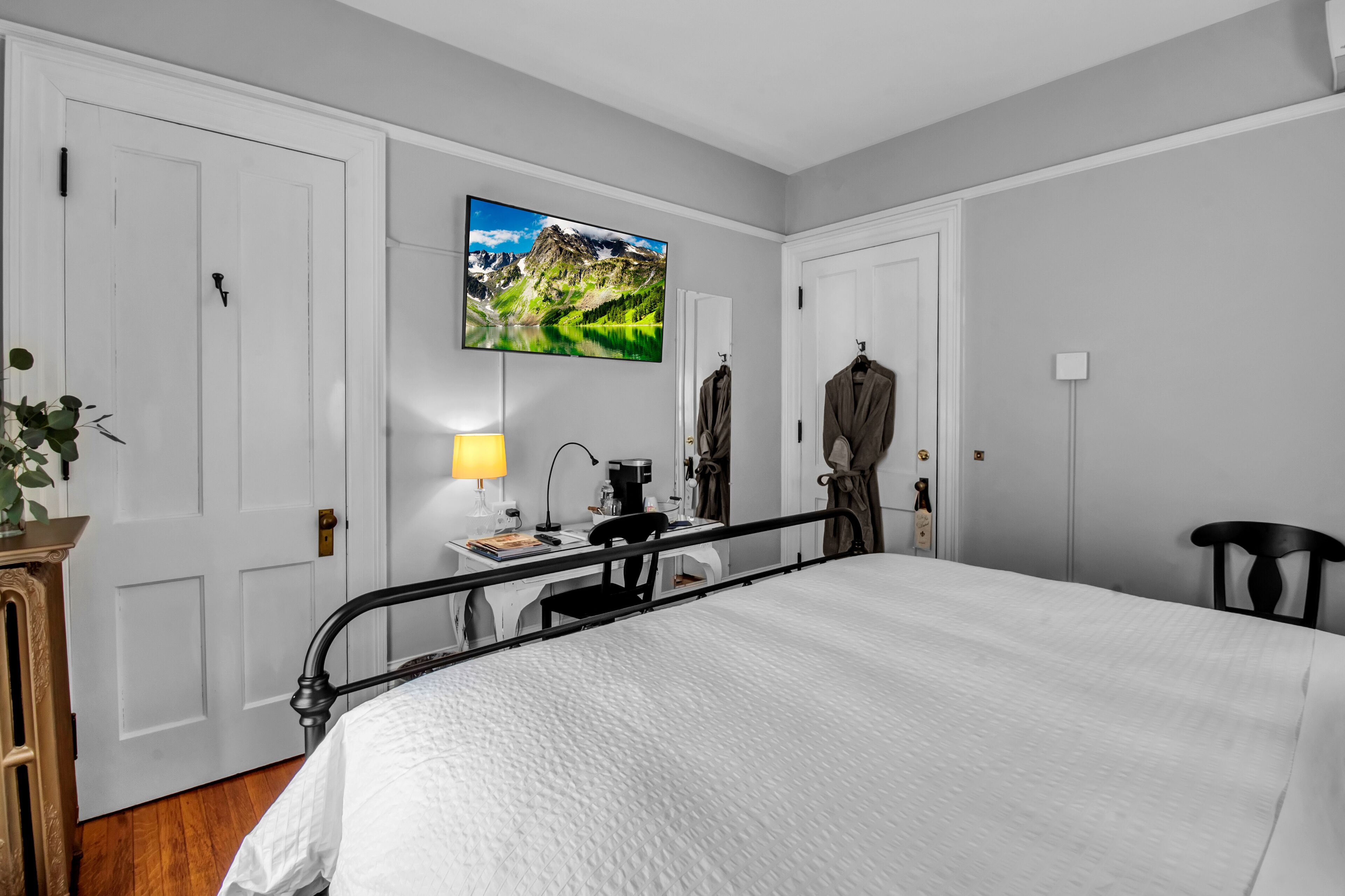 Habitación de hotel con cama, escritorio con lámpara, televisor sobre el escritorio y armario.