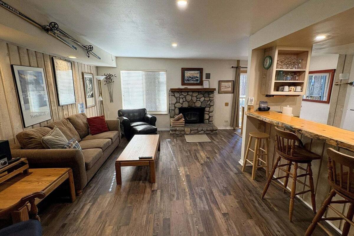 Una sala de estar acogedora con chimenea, una mesa de comedor de madera y una zona de bar con taburetes.