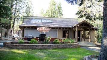 A lodge with a covered patio, a grill, and a stone retaining wall.