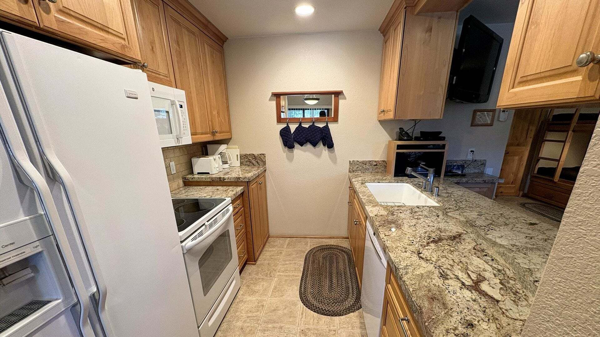 Una cucina compatta con mobili in legno, un forno a microonde, un tostapane e un lavello.