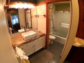 A bathroom with a sink, mirror, and shower.
